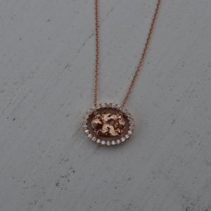 Custom designed east-west pendant with oval Lotus garnet and floating diamond halo in rose gold