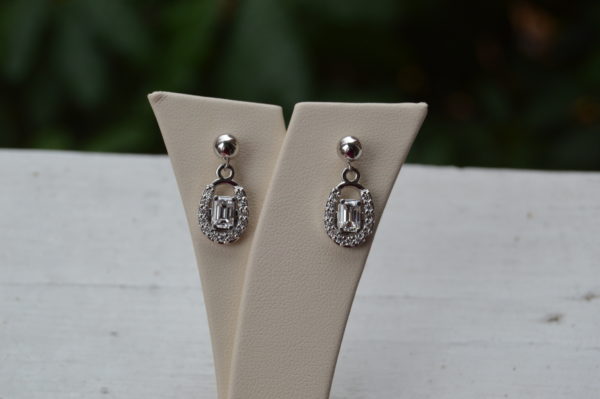 Custom designed dangle earrings with emerald cut diamonds in round diamond horseshoe in white gold