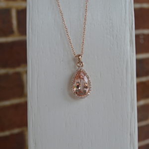 Custom designed pear shaped morganite pendant in rose gold with a diamond halo