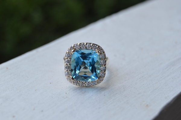 Custom designed lady's fashion ring with cushion cut blue topaz and diamond halo in white gold