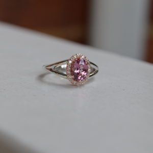 Custom designed lady's ring with oval Lotus garnet and diamond halo in rose and white gold