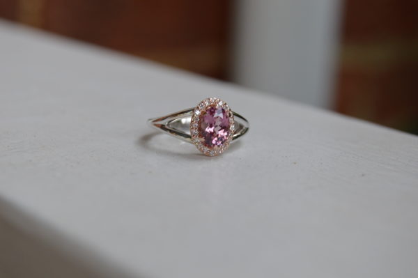Custom designed lady's ring with oval Lotus garnet and diamond halo in rose and white gold