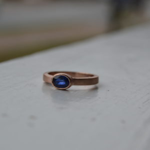 Custom designed oval sapphire rose gold bezel ring with satin finish